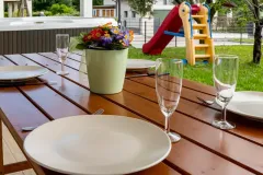 Tavolo in legno allestito nel giardino esterno con area giochi per bambini